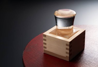 A red tray and a bottle of sake in a Masu on a black background clipart