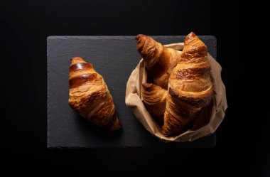 Siyah arka planı olan siyah taştan bir tabakta kruvasan. Yukarıdan manzara