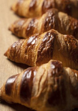 Ahşap arka plana konmuş bir kruvasan. Yakın plan fotoğraf.