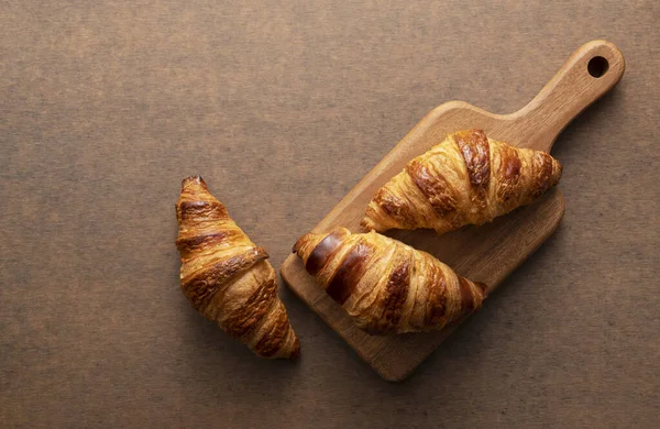 Croissant Umístěný Dřevěné Sekací Desce Dřevěným Pozadím Pohled Shora — Stock fotografie