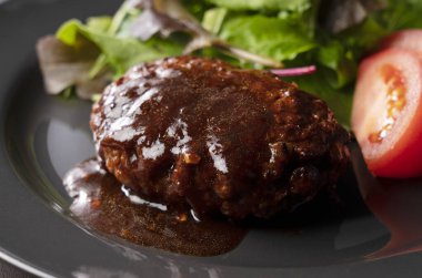 Masaya konmuş bir tabakta servis edilen yarı buzlu soslu hamburger.