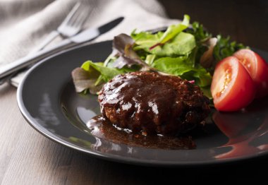 Masaya konmuş bir tabakta servis edilen yarı buzlu soslu hamburger.