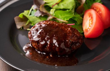 Masaya konmuş bir tabakta servis edilen yarı buzlu soslu hamburger.