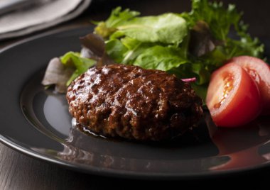 Masaya konmuş bir tabakta servis edilen yarı buzlu soslu hamburger.