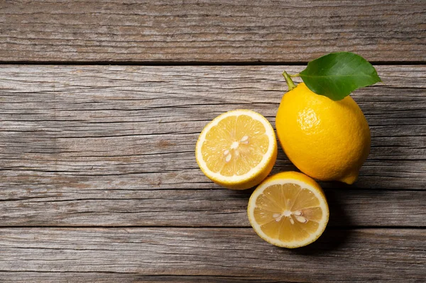 Lemons and halved lemons on the background of a wooden board with copy space. View from directly above