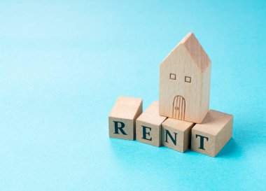 Ahşap oyuncak ev ve kırmızı bloklar mavi arka plana yerleştirilmiş.