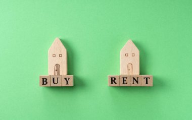 Yeşil arkaplana yerleştirilmiş ahşaptan yapılmış oyuncak evlerle konut imajı satın al veya kirala