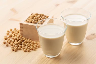 Soy milk in a glass on a wooden background. Soybeans in a masu in the background clipart