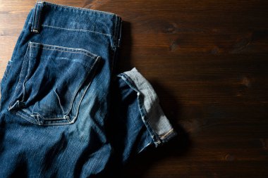 Kopya alanı olan ahşap bir arka planda mavi kot pantolon. Yukarıdan görüntüle