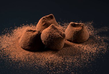 Siyah arka planda kakao tozu ile çikolatalı trüf.