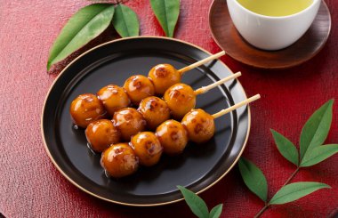 Mitarashi dango ve yeşil çay kırmızı bir Japon tepsisinde. Bir Japon tatlısı olan mitarashi dango 'nun resmi