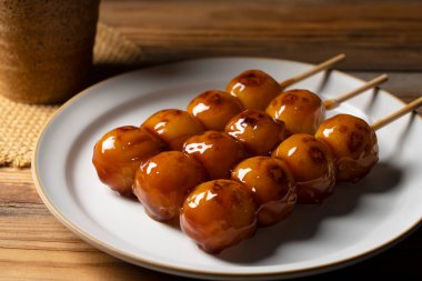 Mitarashi dango ve ahşap arka planda yeşil çay. Bir mitarashi dango resmi, bir Japon tatlısı.