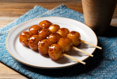 Mitarashi dango ve ahşap arka planda yeşil çay. Bir mitarashi dango resmi, bir Japon tatlısı.