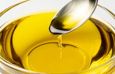 Beyaz arka planda duran bir kasede kaşık zeytinyağı.