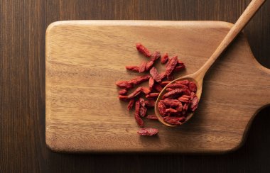 Tahta kesme tahtasına yerleştirilmiş tahta bir kaşıkta kurt üzümü. Doğrudan yukarıdan görüntüle