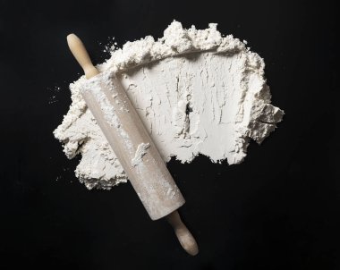 Metin için boş alanı olan fırın arka planı. İğneleri ve unu siyah masaya yuvarla. Üst görünüm