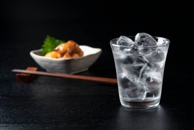 Shochu ve aperatifler siyah ahşap bir arka plana yerleştirilmiş. Japon likörünün görüntüsü..