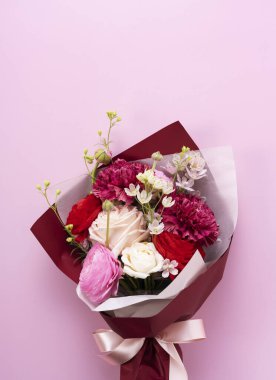 Pembe arka plana yerleştirilmiş bir buket çiçek. Doğrudan yukarıdan bakıldığında.