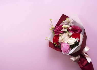 Pembe arka plana yerleştirilmiş bir buket çiçek. Doğrudan yukarıdan bakıldığında.