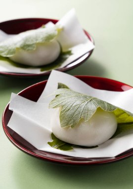 Kashiwa Mochi (pirinç keki) yeşil arka plana yerleştirildi. Kashiwa Mochi bir Japon şekerlemecisidir.