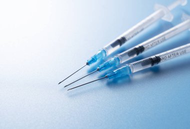 Mavi arka planda bir şırınga var. Aşılama Kavramı