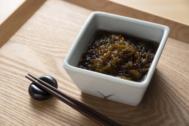 Mozuku ahşap bir tepsiye yerleştirildi. Japon yemeği imajı. Mozuku bir Okinawa lezzetidir. Sirkeyle tatlandırılmış, ipliğe benzeyen koyu renkli bir yosun türü.