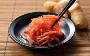 Red pickled ginger placed on a Japanese style background. Eating with chopsticks