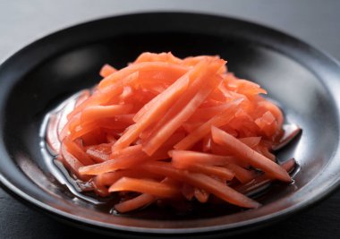 Red pickled ginger placed on a black background. Image of red pickled ginger in Japan.