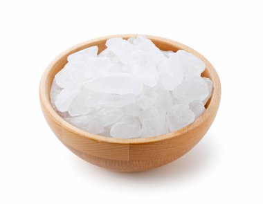 Beyaz arka planda duran tahta bir kasede taş şeker..