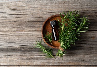 Bir demet taze biberiye ve ahşap arka planda bir şişe gerekli yağ. Doğrudan yukarıdan görüntüle.