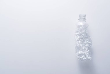 Beyaz arka planda ezilmiş plastik bir şişe. Geri dönüşüm ve ekoloji kavramı.