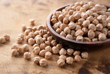 Ahşap bir arka planda ahşap bir çanakta kurumuş nohut..