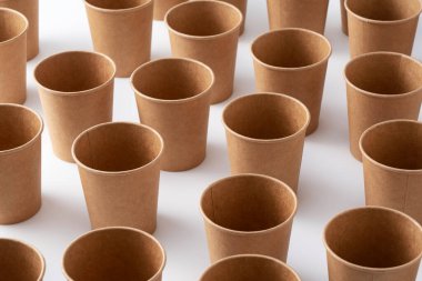 Beyaz arka planda bir sürü kahverengi geri dönüşümlü kağıt bardak var. Sıfır atık kavramı.