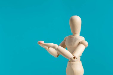 Mavi arka planda hapları olan tahta manken. İlaç ve takviye maddeleri kavramı.