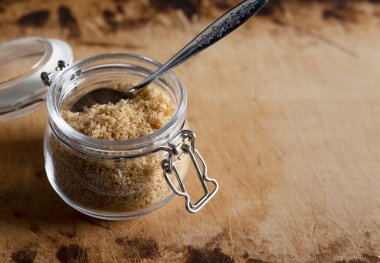 Esmer şeker eski ahşap bir arka planda cam bir kabın içinde. Metin uzayı. 