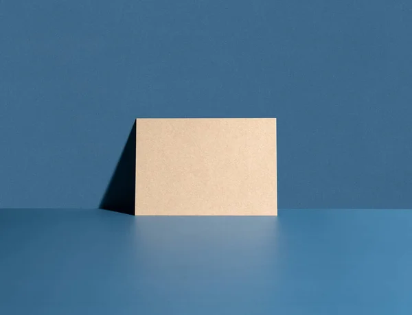 茶色のカードは青い壁にもたれている 招待モックアップ 長い影 — ストック写真