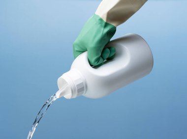 Şişeyi al ve deterjanı doldur. Mavi arka plan. Temizlik kavramı.