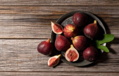 Bir sürü incir ve incir, ahşap bir zemine karşı bir tabak seti. Yukarıdan görüntüle.