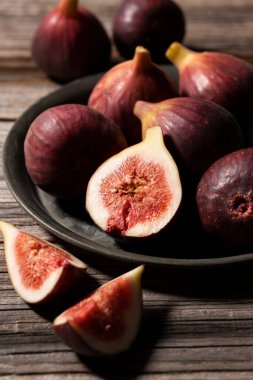 Bir sürü incir ve incir, ahşap arka planda bir tabakta.. 