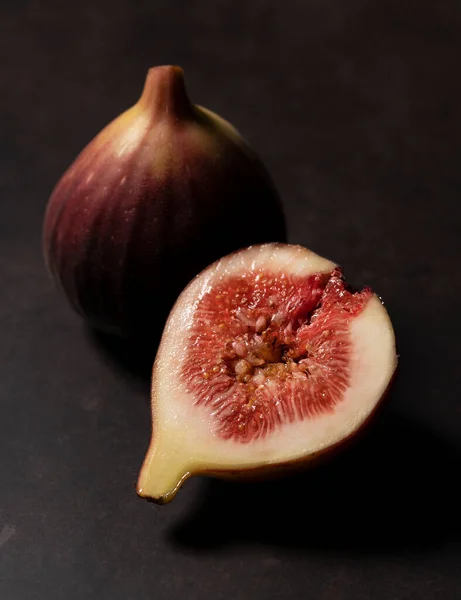Figs and cut figs on a dark background. Image of figs. Close-up.