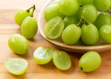 Bir sürü Shine-Muscat üzümü ve tahta bir arka planda Shine-Muscat üzümleri. Beyaz üzümler. Japon üzümleri.