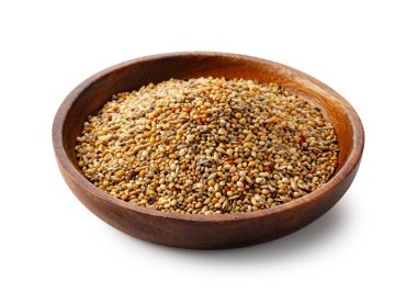 Beyaz arka planda izole edilmiş ahşap bir kasede çeşitli taneciklerle kuş yemi karışımı.