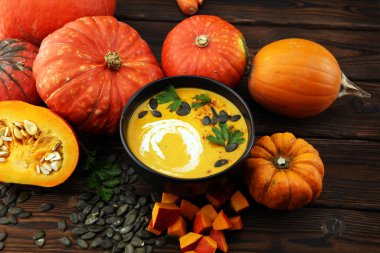 Kızarmış balkabağı ve kremalı havuç çorbası ve kabak çekirdeği ve ahşap kaplama otlar..