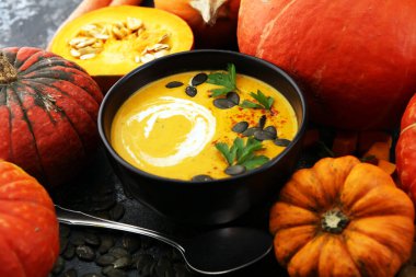 Kızarmış balkabağı ve kremalı havuç çorbası ve kabak çekirdeği ve ahşap kaplama otlar..