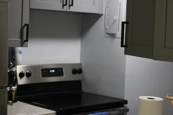 La cuisine grise moderne dispose d'armoires avant plates gris foncé jumelées avec des comptoirs en quartz blanc et un dosseret de tuiles linéaires gris brillant. Northwest, États-Unis — Photo