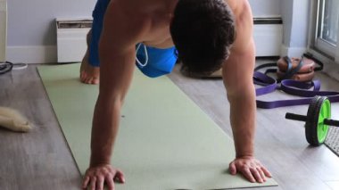 Kaslı adam evinde şınav çekiyor.