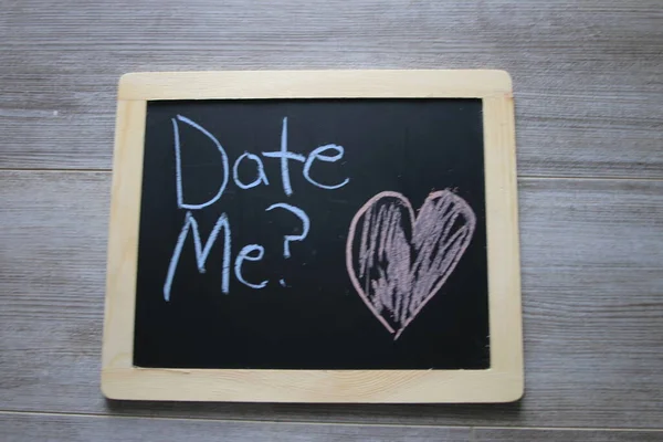 Date me wrote on a black chalkboard — стоковое фото