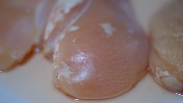 Añadir condimento a la pechuga de pollo cruda en una tabla de cortar — Vídeo de stock