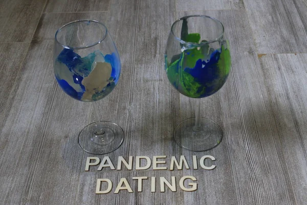 The word pandemic dating next to two wine glasses. Theme of going on dates during pandemic.
