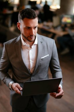 Resmi olarak genç adam dizüstü bilgisayarı tutuyor ve başka yere bakıyor.